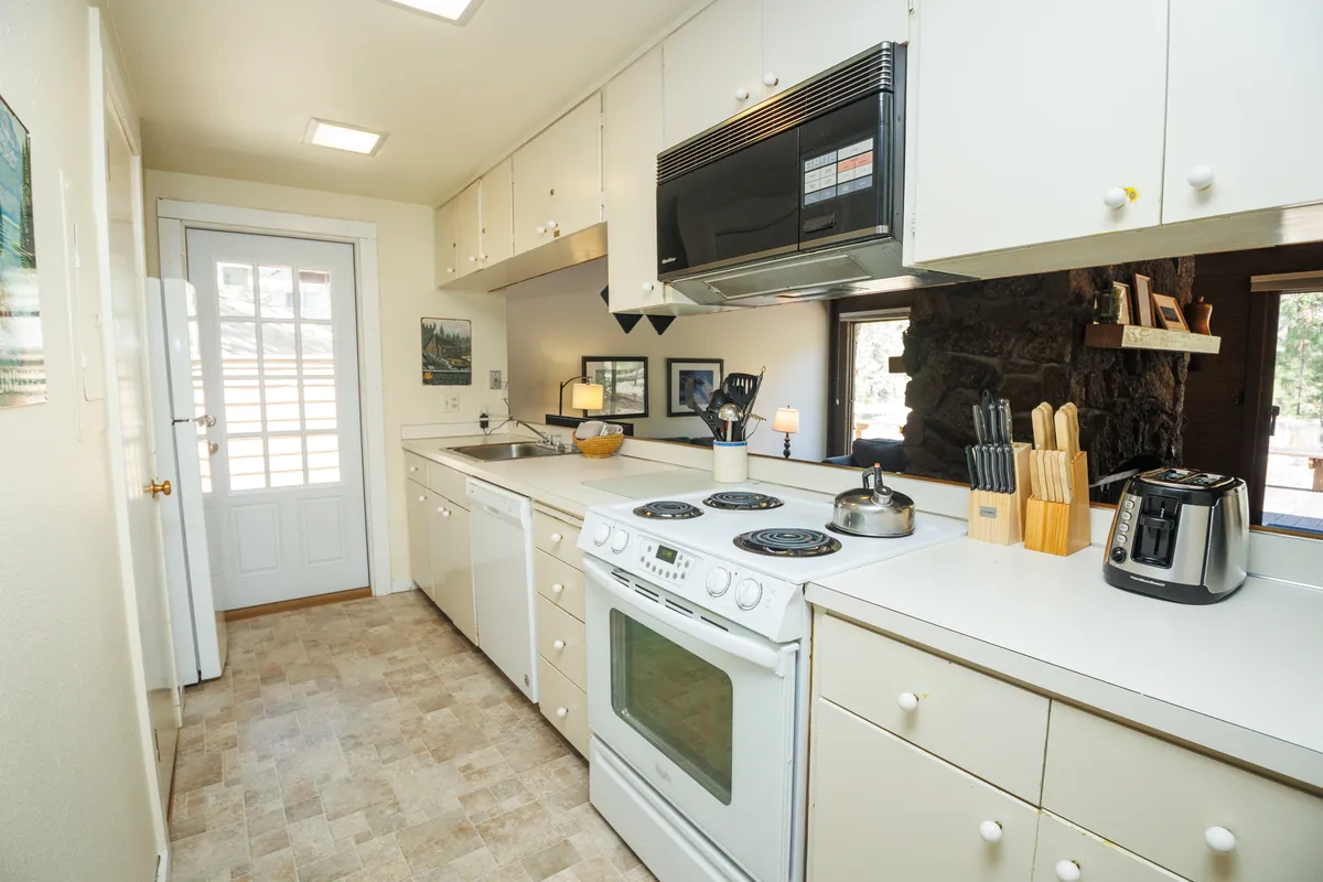 A bright, welcoming kitchen scene with modern appliances, a spacious countertop, open shelving, and a window offering a pleasant outdoor view. The layout encourages social interaction during meal prep and family gatherings.