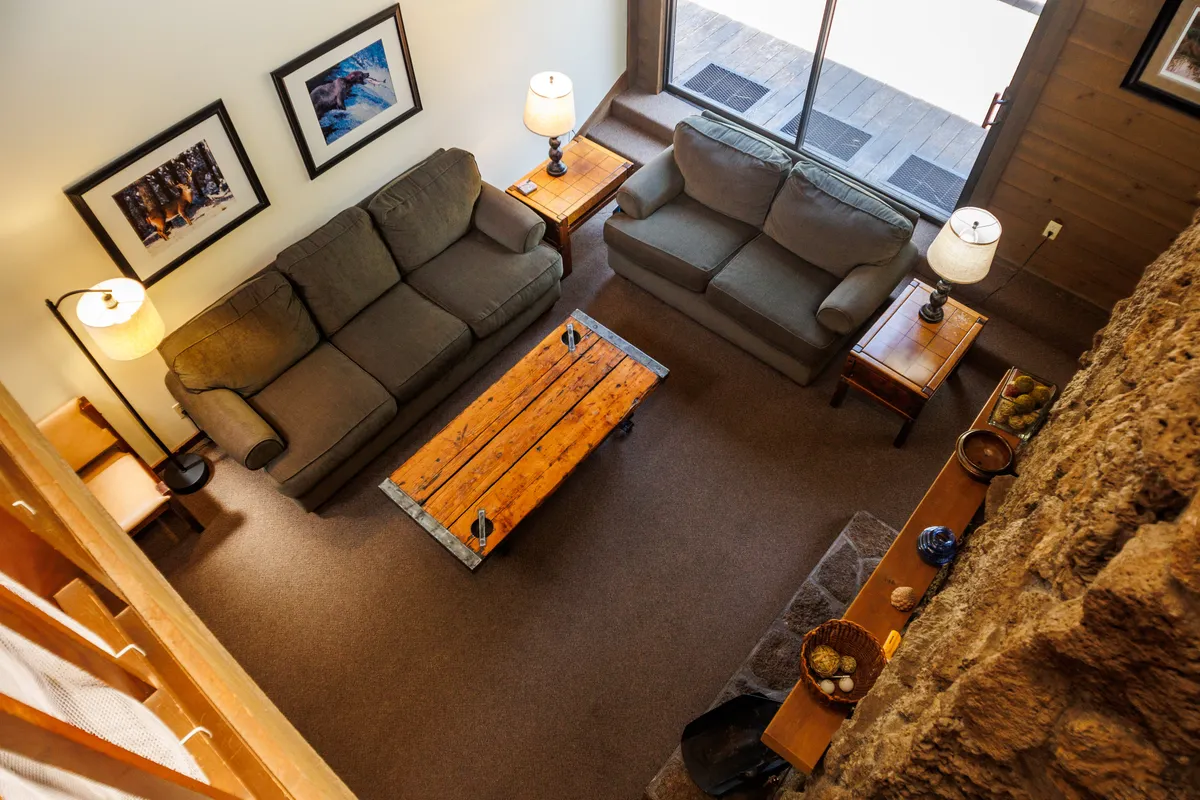 This cozy living area features inviting sofas, a coffee table, lamps, and tasteful art on the wall, creating a perfect spot for relaxing, socializing, playing games, or sharing stories. The layout encourages group interaction and comfort.